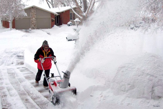 Snow remover using a snow blower to clear a driveway